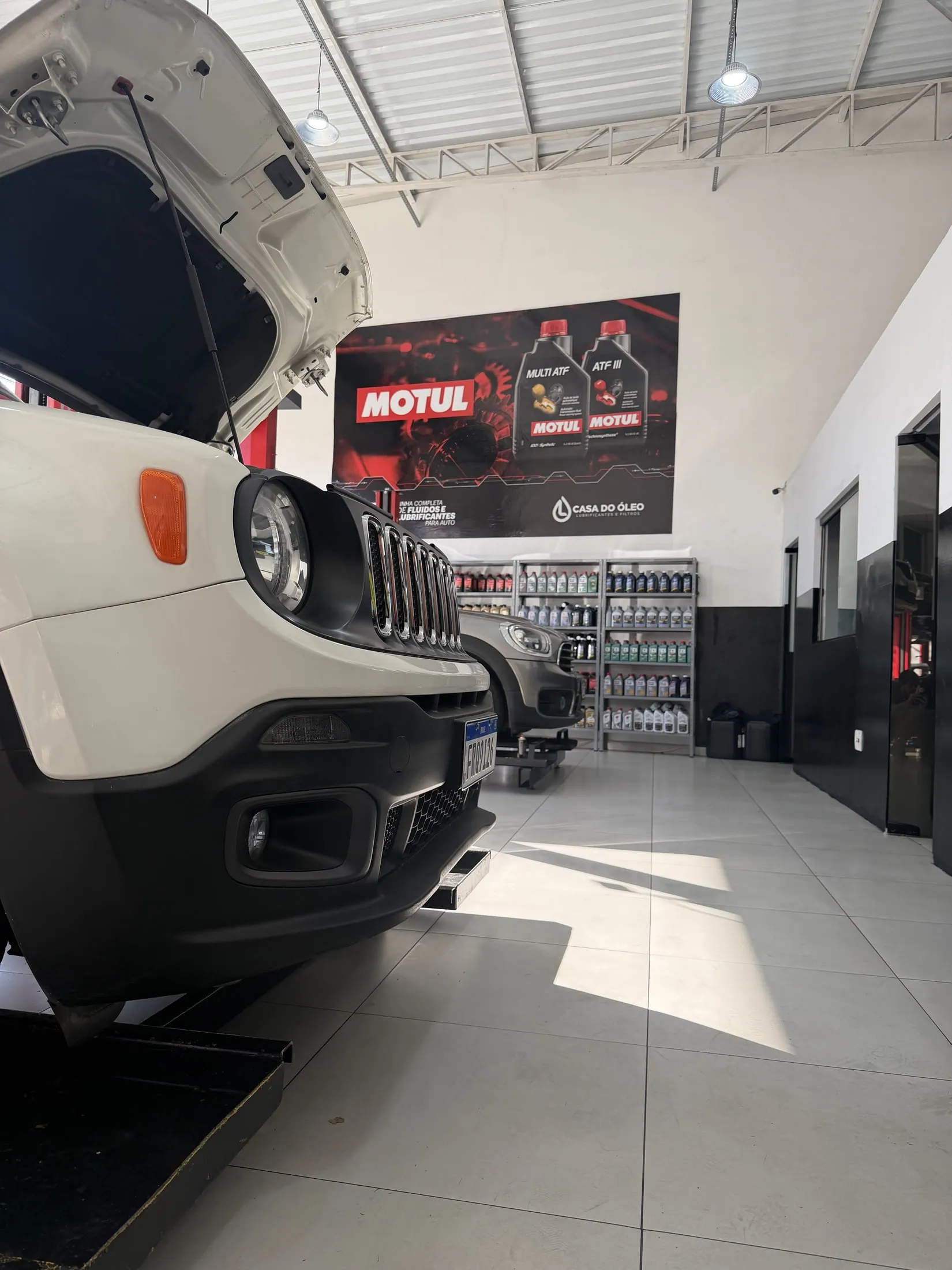 Veículo posicionado no box, com a loja de produtos ao fundo